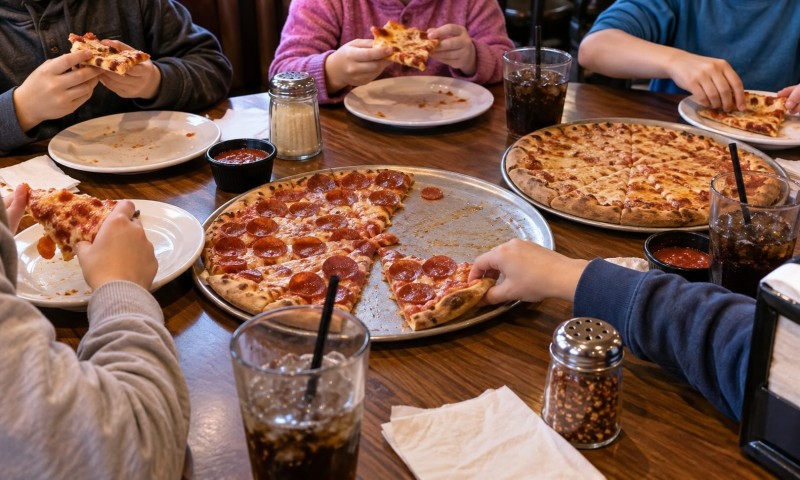 Kids eating pizza sat at a table